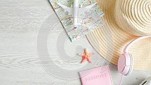 Travel or summer vacation concept on wooden table. Top view airplane model, map, beach hat, pink headphones and passport document