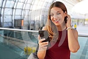 Travel and technology. Excited young woman receiving good news on her smartphone waiting for boarding in airport terminal