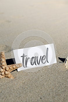 TRAVEL text on paper greeting card on background of starfish seashell summer vacation decor. Sandy beach sun coast