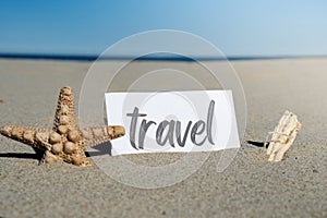 TRAVEL text on paper greeting card on background of starfish seashell summer vacation decor. Sandy beach sun coast