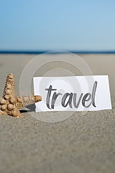 TRAVEL text on paper greeting card on background of starfish seashell summer vacation decor. Sandy beach sun coast