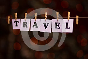 Travel text on papers with clothespins with garland bokeh on background