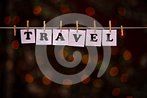 Travel text on papers with clothespins with garland bokeh on background