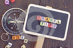 TRAVEL TIPS word block on wooden signage and compass.faded effect color photo