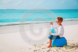 travel to beach-little boy with toy plane, globe and luggage at sea