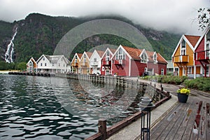 Travel to Norway, a small village on the shore of the fjord, bright houses stand in a semicircle on the embankment, behind the