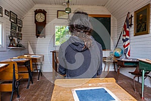 Travel to the past. Man sits in old class of 20th