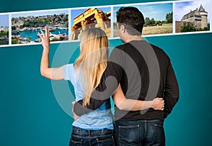 Travel and tourism concept. Embracing couple scrolling summer holidays images. Woman and man selecting travel photos on digital d