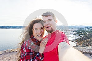 Travel, tourism and vacation concept - Happy married couple taking selfie near a sea