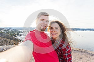 Travel, tourism and vacation concept - Happy married couple taking selfie near a sea