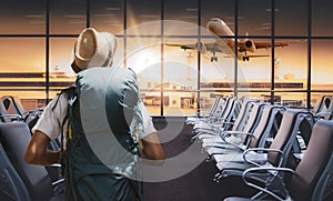 Travel tourist standing with backpack watching sunset at airport window. Passenger seat in departure lounge for see airplane, View