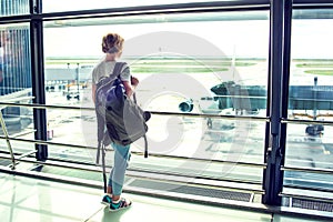 Travel tourist standing with luggage watching at airport window.