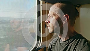 Travel by train. The face of a man looking out the window of a train car in winter.