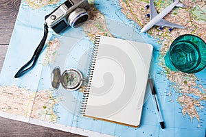 Cestovanie , výlet, prázdniny, cestovný ruch mockup zblízka kompas, pohár vody note pad, pero a hračiek v lietadle a turistické mapy na drevený stôl.