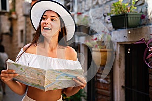 Travel vacation city concept. Young happy traveler woman with map walking