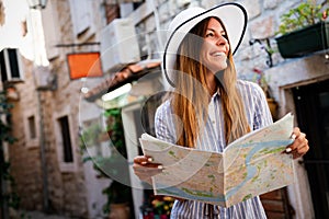 Travel vacation city concept. Young happy traveler woman with map walking