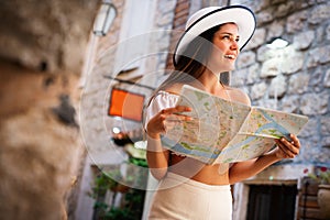 Travel vacation city concept. Young happy traveler woman with map walking