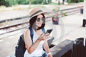 Travel and vacation concept,Happy asian woman tourist using cell phone and waiting train at train station