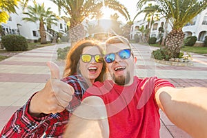 Travel, vacation, summer and holiday concept - Nice couple taking selfie on hotel court