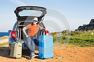Travel, vacation, summer trip and people concept - man is going on holiday, suitcases in the trunk of a car