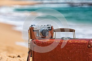 Travel vintage suitcase and camera on a beach