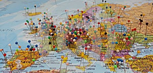 Travel Visitors Marking Locations on a colorful World map with push pins.