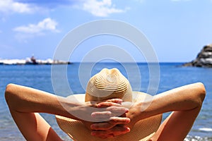 Travel, vocation, holiday concept. Woman in hat is lying on deckchair on beach by sea.