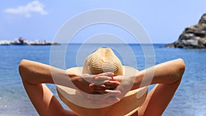 Travel, vocation, holiday concept. Woman in hat is lying on deckchair on beach by sea.