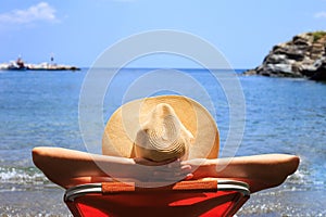 Travel, vocation, holiday concept. Woman in hat is lying on deckchair on beach by sea