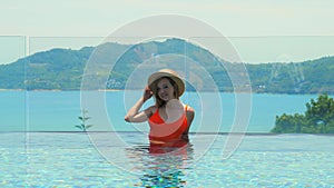 Travel woman in bikini and summer hat enjoys sea view of luxury hotel spa