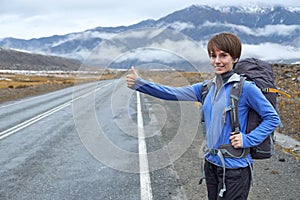 Travel woman hitchhiking. Beautiful young female hitchhiker by t