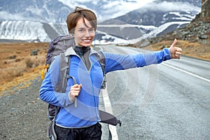 Travel woman hitchhiking. Beautiful young female hitchhiker by t