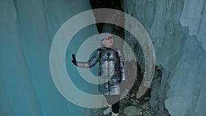 Travel woman on ice cave of Lake Baikal. Trip to winter island. Girl backpacker is walking of ice grot. Traveler looks