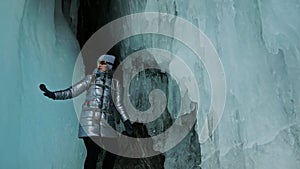 Travel woman on ice cave of Lake Baikal. Trip to winter island. Girl backpacker is walking of ice grot. Traveler looks