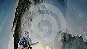 Travel woman on ice cave of Lake Baikal. Trip to winter island. Girl backpacker is walking of ice grot. Traveler looks