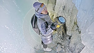 Travel woman on ice cave of Lake Baikal. Trip to winter island. Girl backpacker is walking of ice grot. Traveler looks