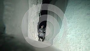 Travel woman on ice cave of Lake Baikal. Trip to winter island. Girl backpacker is walking of ice grot. Traveler looks