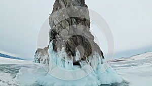 Travel of woman on ice of Lake Baikal. POV view. Trip to winter island. Girl is walking at foot of ice rocks. Traveler