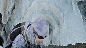 Travel of woman on ice of Lake Baikal. Trip to winter island. Girl is walking at foot of ice rocks. Traveler looks at