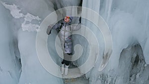 Travel of woman on ice of Lake Baikal. Trip to winter island. Girl is walking at foot of ice rocks. Traveler looks at