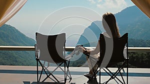 Travel woman sitting in chair near camping tent, enjoy mountain view