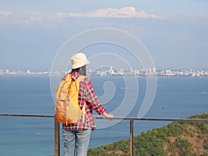 Travel , Women wearing Blue jeans and red plaid shirt and backpacking yellow at viewpoint on mountain are looking at the sea