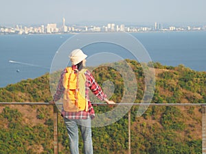Travel , Women wearing Blue jeans and red plaid shirt and backpacking yellow at viewpoint on mountain are looking at the sea
