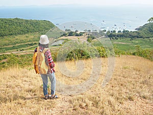 Travel , Women wearing Blue jeans and red plaid shirt and backpacking yellow at viewpoint on mountain are looking at the sea