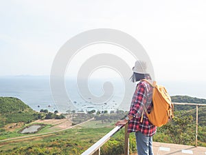 Travel , Women wearing Blue jeans and red plaid shirt and backpacking yellow at viewpoint on mountain are looking at the sea