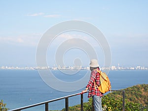 Travel , Women wearing Blue jeans and red plaid shirt and backpacking yellow at viewpoint on mountain are looking at the sea