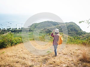 Travel , Women wearing Blue jeans and red plaid shirt and backpacking yellow at viewpoint on mountain are looking at the sea