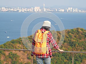 Travel , Women wearing Blue jeans and red plaid shirt and backpacking yellow at viewpoint on mountain are looking at the sea