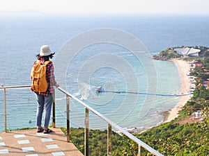 Travel , Women wearing Blue jeans and red plaid shirt and backpacking yellow at viewpoint on mountain are looking at the sea