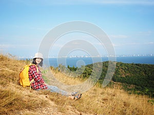 Travel , Women wearing Blue jeans and red plaid shirt and backpacking yellow at viewpoint on mountain are looking at the sea